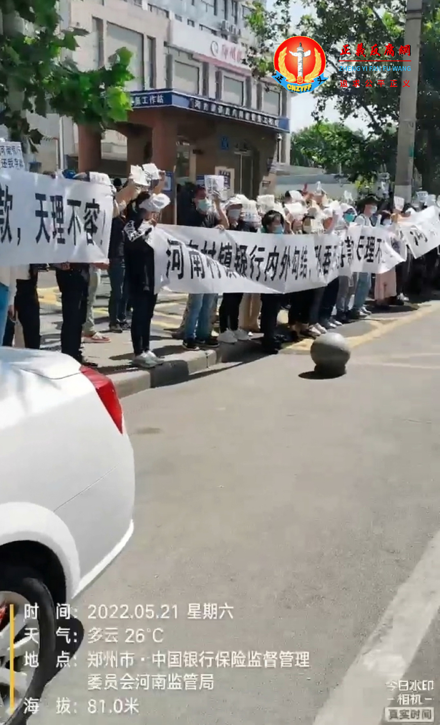5月21日，约数几十人河南村镇银行储户在河南银保监局门前拉着横幅并高喊“还钱”的口号等。.png