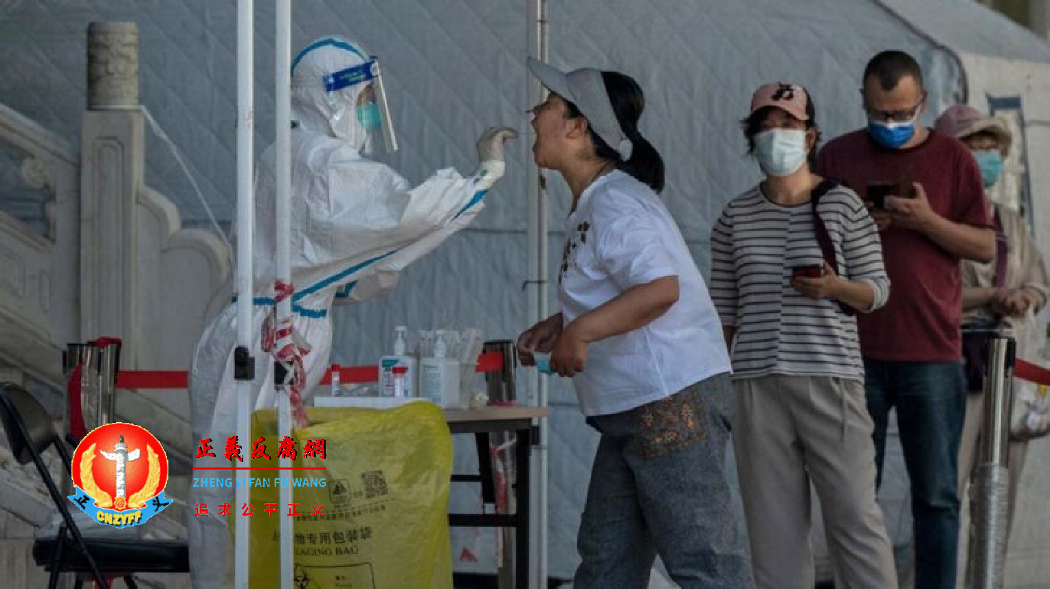 2022 年 5 月 26 日，北京街头的一个检测点，一名穿着防护服的工作人员，正在对一名妇女进行病毒（COVID-19）核酸检测采样。.png
